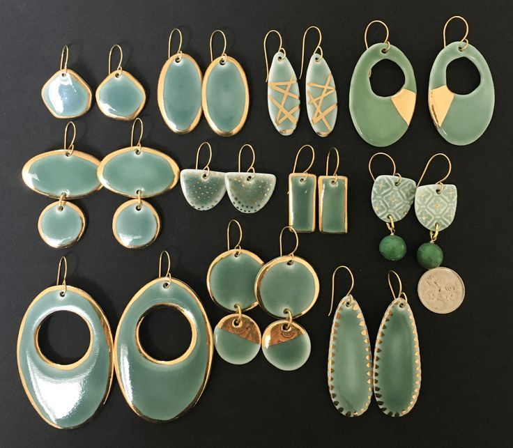 a collection of earrings and pendants on a black surface with a penny in the foreground