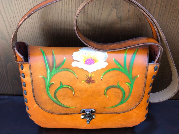 With the floral embroidery trend taking over the fashion scene, these bags with their floral work painted over the leather bag lends an eye-catching detail that is very bohemian. Over rustic brown leather canvas, the colored petals enliven the worn look of these RETRO style bags. The shape of the bag itself is a favorite as it is easy to carry and quite aesthetically-attractive. As the cooler season takes shape, these bags would be fitting for outfits that are earthy in hues. Or if you simply wa Artistic Bags For Everyday Use In Spring, Vintage Hand Painted Rectangular Bag, Artisan Hand Painted Brown Bags, Bohemian Hand Painted Shoulder Bag For Everyday Use, Artisan Leather Bags Hand Painted, Artistic Hand Painted Leather Shoulder Bag, Artisan Rectangular Shoulder Bag Hand Painted, Artisan Hand Painted Rectangular Shoulder Bag, Hand Tooled Satchel Bag For Gifts