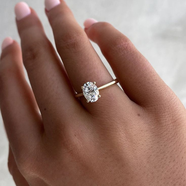 a woman's hand with a diamond ring on top of her left hand,