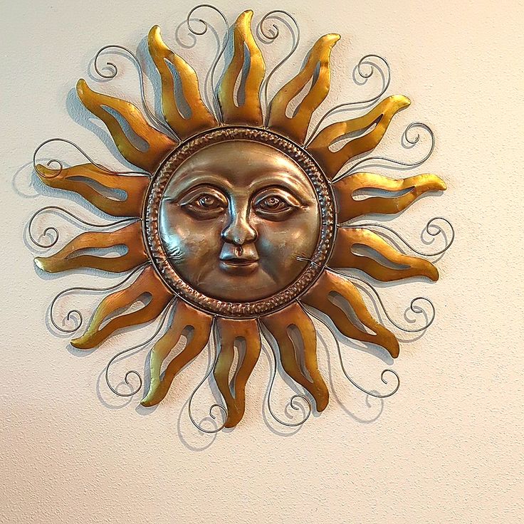 a metal sun face mounted to the side of a wall