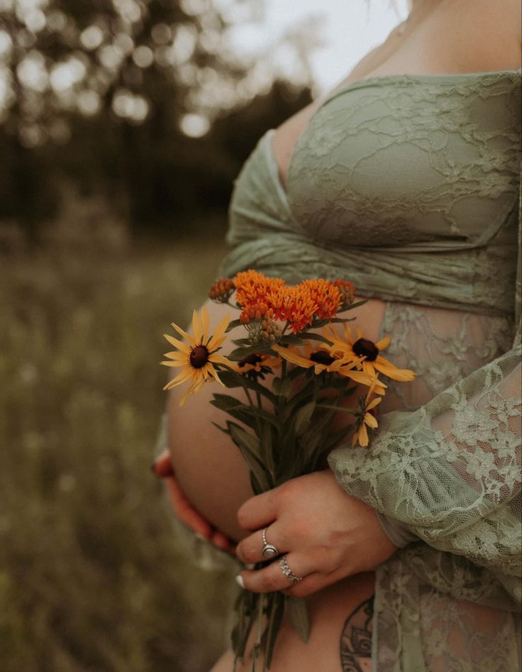 a pregnant woman holding flowers in her belly