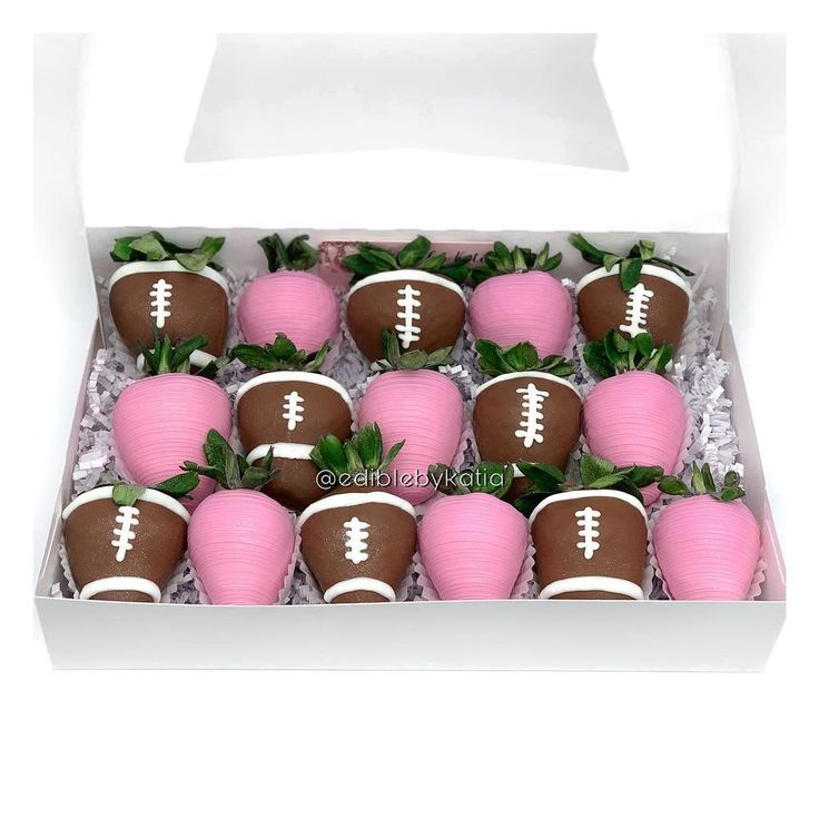 chocolate covered strawberries in a white box with pink frosting and football decorations on them