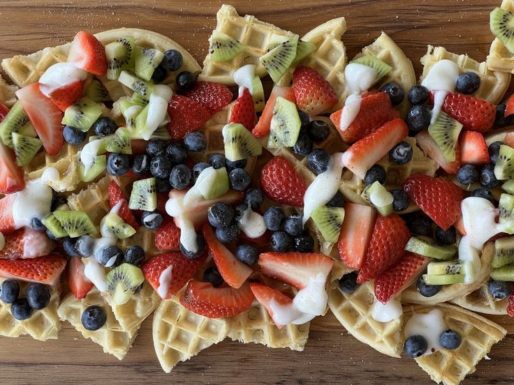 waffles topped with fruit and cream on top of a wooden table