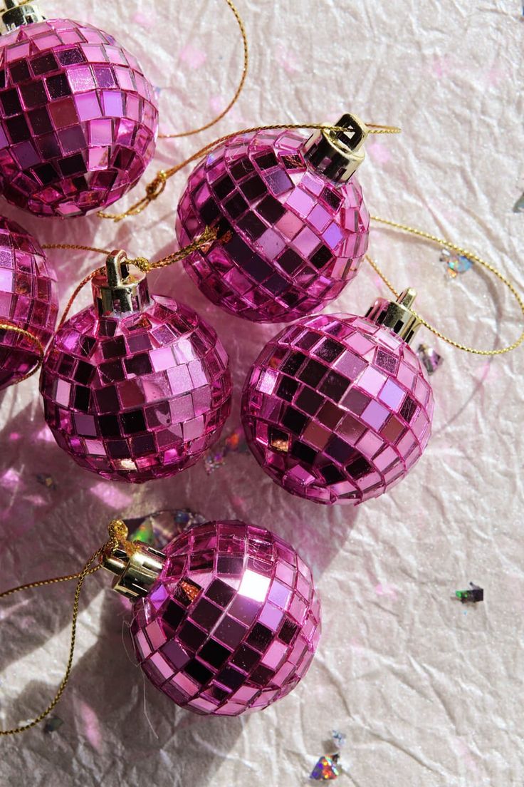 several pink christmas ornaments on a white tablecloth with confetti sprinkles