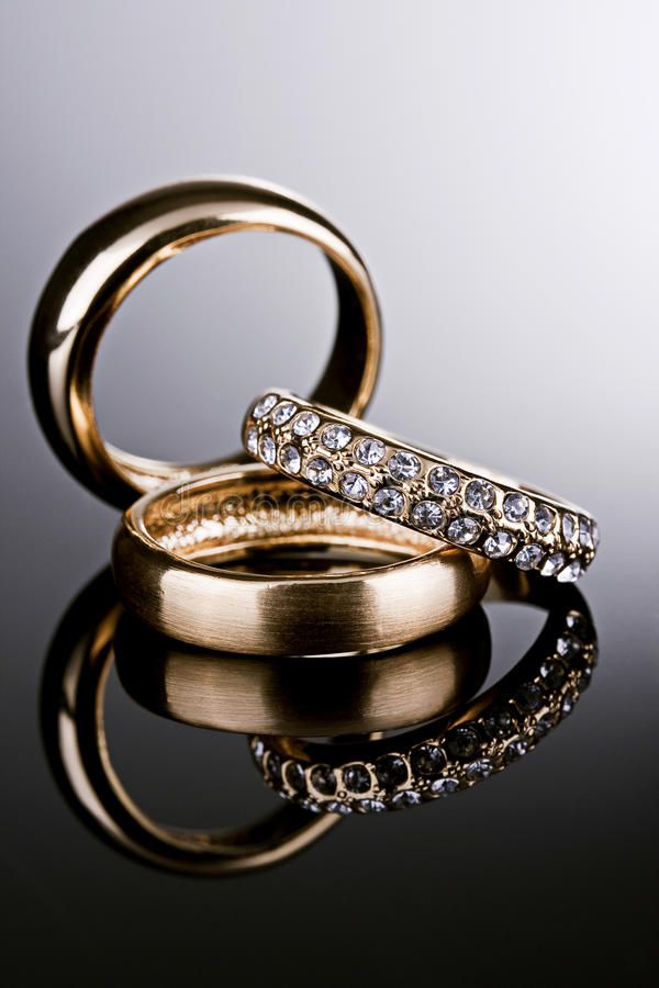 two gold wedding rings sitting on top of each other with diamonds in the middle and sides