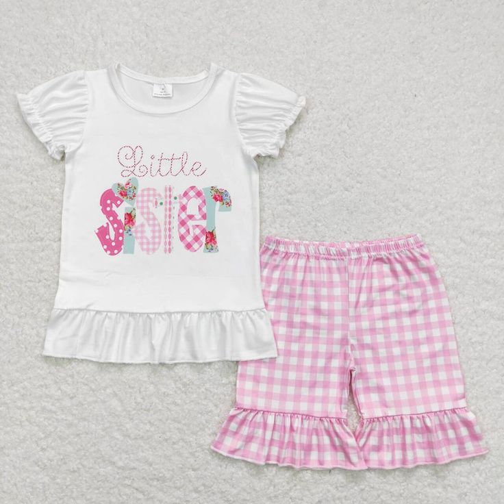 a white shirt and pink checkered shorts are sitting on the floor next to each other