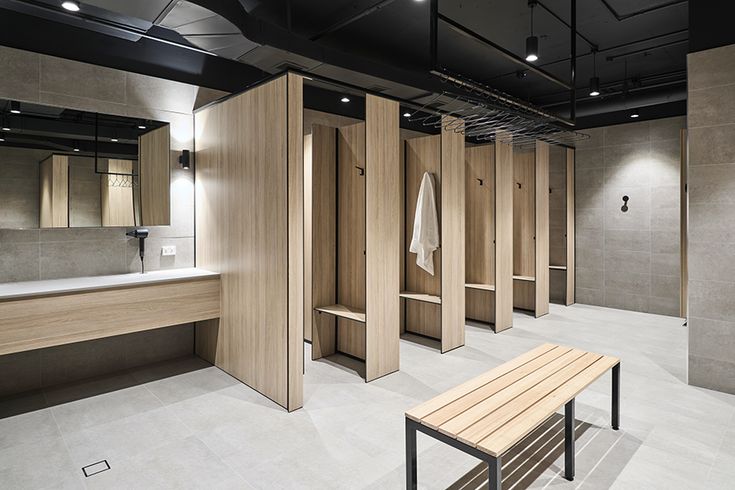 an empty bathroom with wooden stalls and white towels hanging on the walls, along with a bench