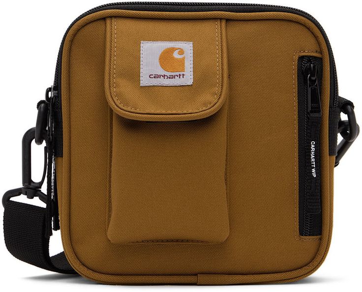 Water-repellent two-compartment polyester canvas shoulder bag in tan. · Detachable and adjustable webbing shoulder strap · Flap pocket, zip pocket, and logo patch at face · Zip closures · Polyester canvas lining in black · H6.5 x W6 x D2.5 in Supplier color: Hamilton brown | Carhartt Work In Progress Tan Essentials Bag Carhartt Work In Progress, Essential Bag, Canvas Shoulder Bag, Work In Progress, Flap Pocket, Repellent, Water Repellent, Patch Logo, Fashion Backpack