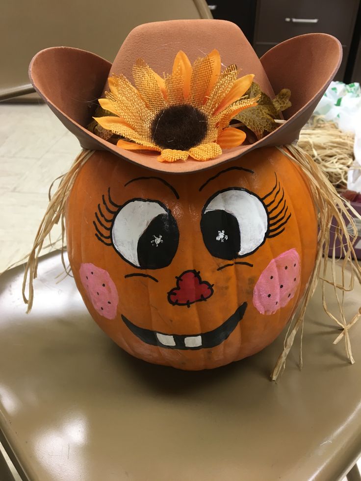 a pumpkin with a cowboy hat on it's head sitting on top of a table