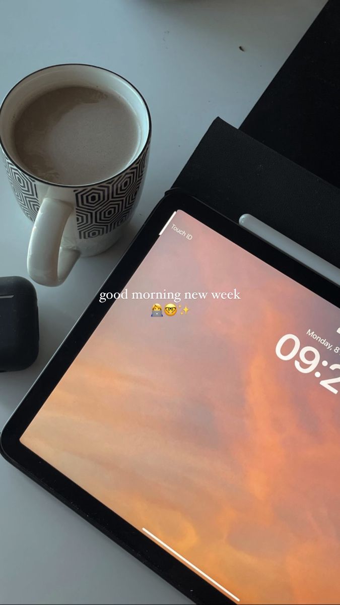 a tablet computer sitting on top of a table next to a cup of coffee and an alarm clock