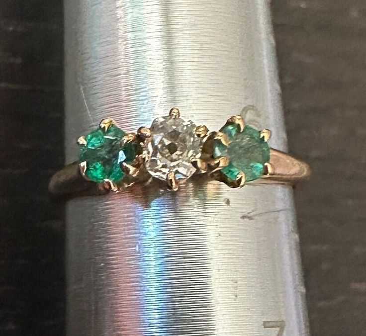 Antique 14K Emerald & Diamond ring size 6, weight 2.2 grams.  Antique old white European cur center Diamond(4mm-approx 1/4 carat) with two genuine richly colored deep green Emeralds on each side-High prong setting.  The classic trinity horizontal design. Vintage Style Emerald Cluster Ring In Yellow Gold, Antique Multi-stone Round Emerald Ring, Antique Round Multi-stone Emerald Ring, Vintage Emerald Diamond Ring In Green, Classic Green Multi-stone Diamond Ring, Antique Green Oval Diamond Ring, Green 14k Stamped Diamond Ring, Vintage Green Emerald Ring With Rose Cut Diamonds, Vintage Green Emerald Diamond Ring