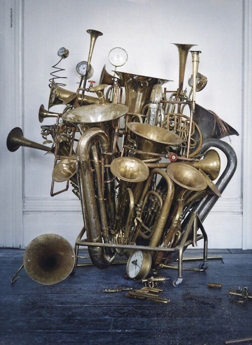 a bunch of brass musical instruments stacked on top of each other in front of a white door