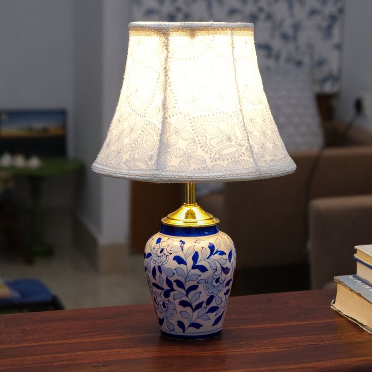 a blue and white lamp sitting on top of a wooden table next to a book