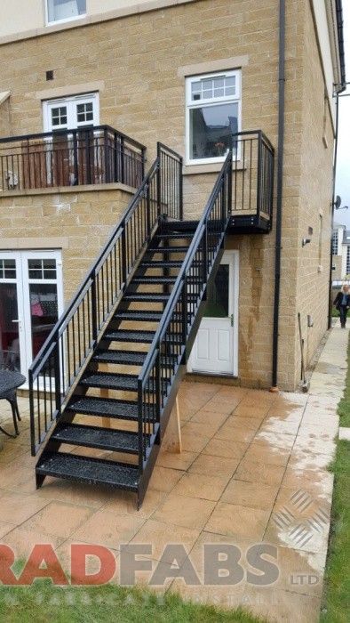 a black stair case next to a brick building