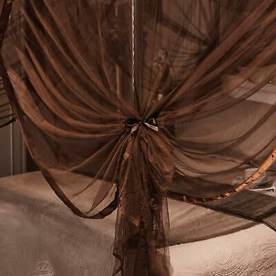 an unmade bed with sheer curtains on it