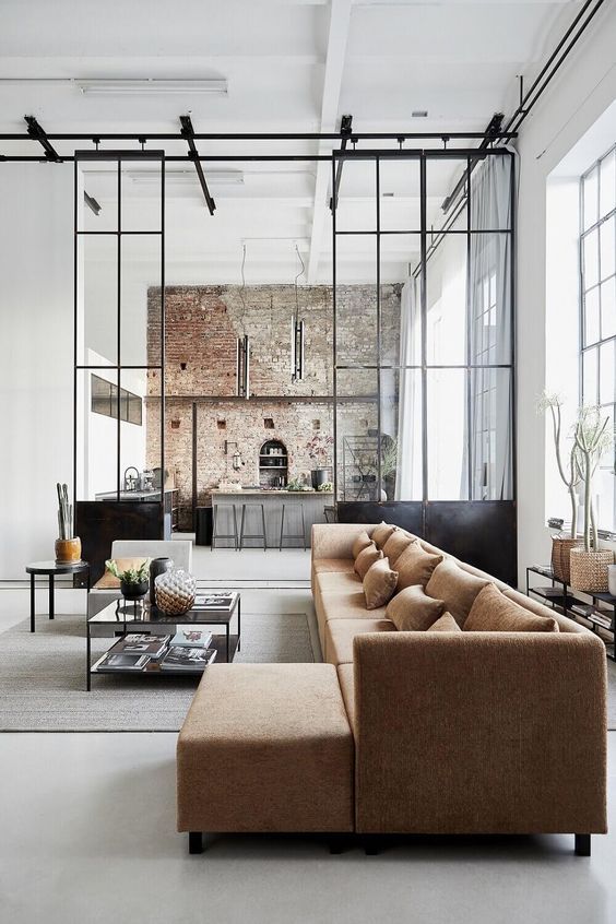 a living room filled with lots of furniture next to a brick wall covered in windows