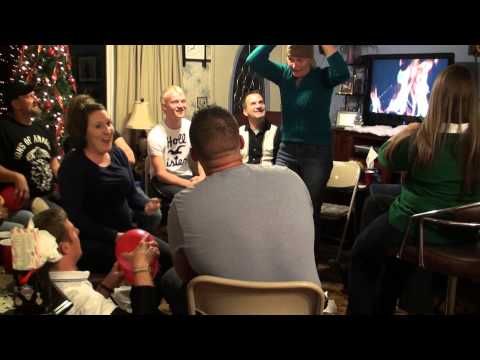 a group of people sitting around in front of a christmas tree and watching something on tv