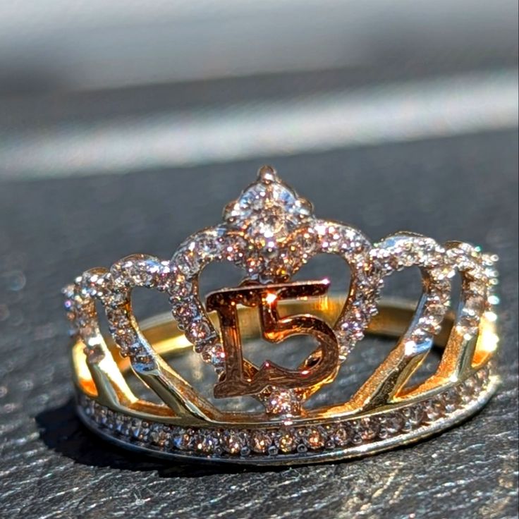 a gold and diamond crown ring sitting on top of a table