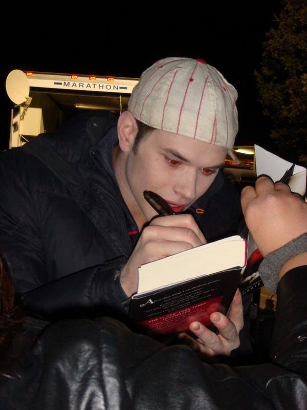 a man holding a book and looking at it while another person holds something in his hand