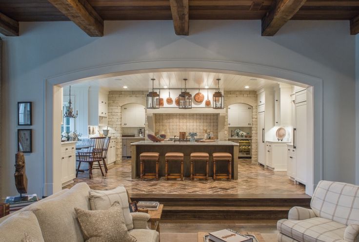 an open concept kitchen and living room with wood beams in the ceiling, hardwood flooring