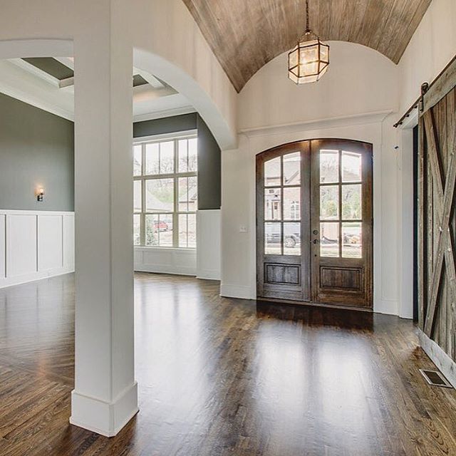 an empty living room with wood floors and large windows