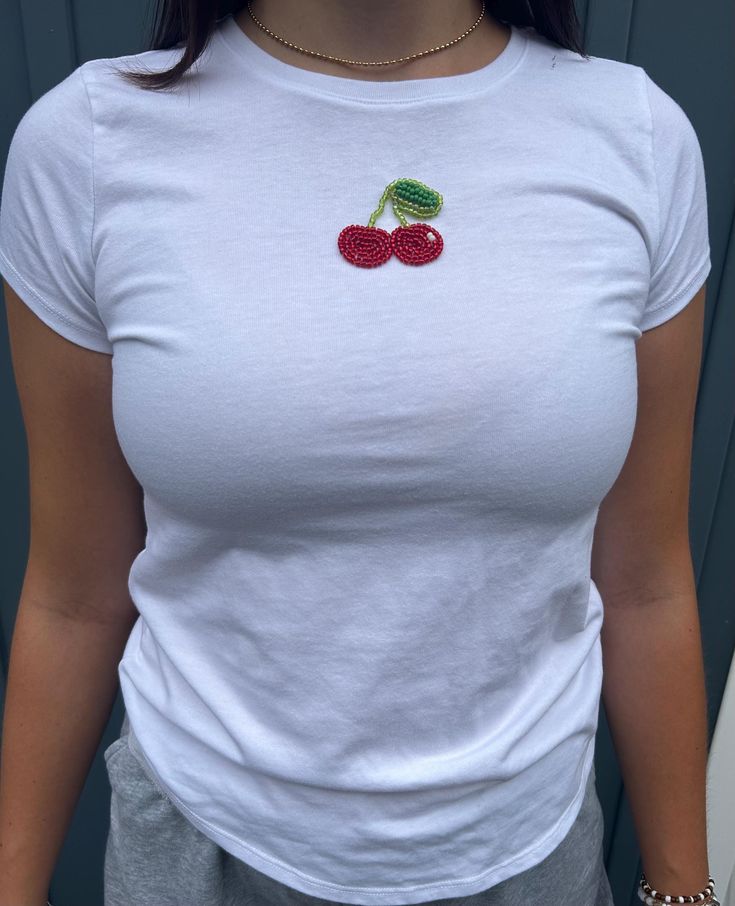 a woman wearing a white shirt with cherries on it