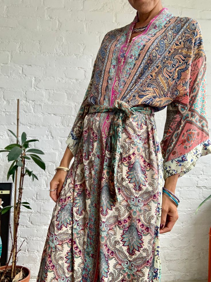 "This is super stylish kimono robe made free size with wrap tie closing  easy fit all ladies, feels very comfortable and light  Can be used as an everyday robe or boho street style over all with jeans and t shirt  It is made one of a kind, patchwork from varieties of different floral silky materials  MEAESURE shoulder 17\" length 55\" MATERIAL *poliester and * no lining more available at  https://www.etsy.com/shop/AltheaStores? CARE INSTRUCTIONS  * Wash in warm water * Hand wash recommended * Ha Bohemian Flowy Long Sleeve Kimono, Bohemian V-neck Robe For Loungewear, Bohemian V-neck Kaftan With Tie Waist, Bohemian Long Sleeve Rayon Kimono, Bohemian Spring Kimono With Tie Waist, Bohemian Rayon Kimono For Loungewear, Bohemian Style Rayon Kimono For Loungewear, Festival Silk Kimono With Flowy Fit, Bohemian Kimono With Tie Waist And Kimono Sleeves