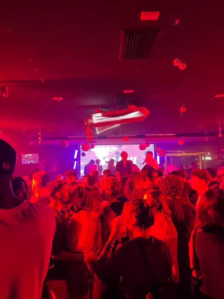 a large group of people in a room with red lights on the ceiling and floor