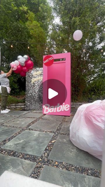 a woman is throwing balloons in the air at an outdoor party with pink and silver decorations