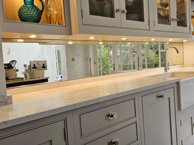 a kitchen with white cabinets and marble counter tops