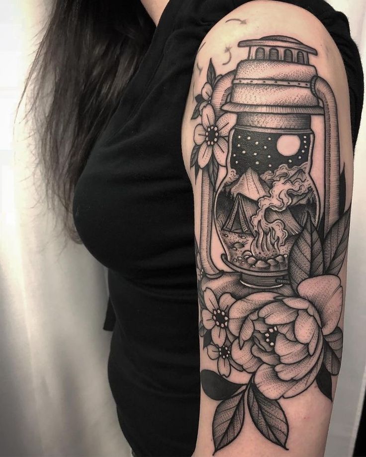 a woman with a black and white tattoo on her arm is holding a jar filled with flowers