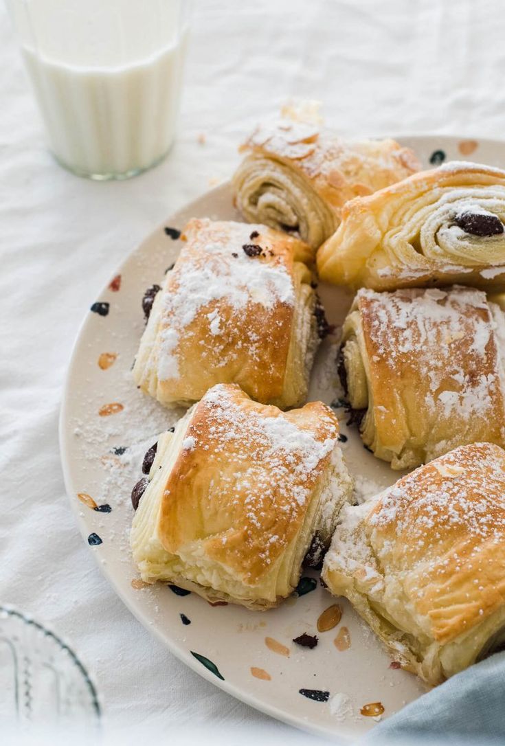 a white plate topped with pastries next to a glass of milk