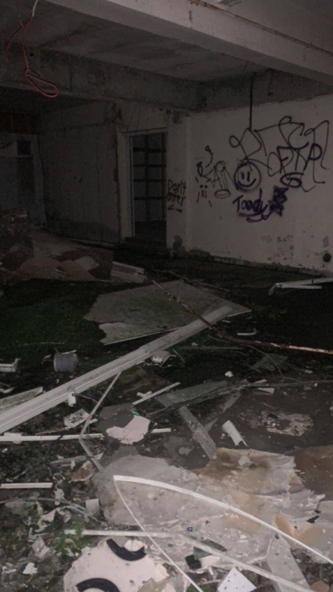 an abandoned building with graffiti on the walls and debris in the floor, along with broken windows