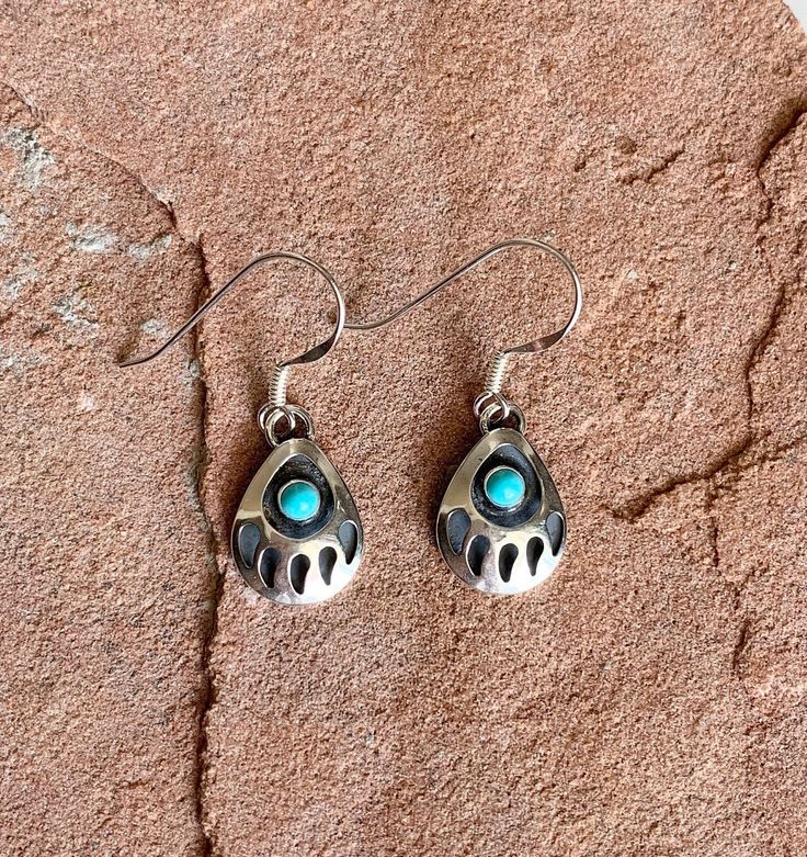 "Vibrant, Southwestern, and versatile dangle earrings that are handcrafted by me! These earrings are comfortable and lightweight, making it ideal for everyday wear. They add a pop of color and a Southwestern vibe. It would be a beautiful addition to your outfit! The stone is American Turquoise. All findings are 925 sterling silver. Measurements: 1\" long and a 10x13mm sterling silver bear paw with 2mm turquoise stone in the center. The earrings are dangle earrings with an ear wire. Handcrafted i Turquoise Nickel-free Southwestern Teardrop Earrings, Handmade Southwestern Turquoise Teardrop Earrings, Handmade Turquoise Teardrop Earrings Southwestern Style, Southwestern Adjustable Teardrop Earrings, Adjustable Southwestern Teardrop Earrings, Handmade Turquoise Teardrop Earrings In Southwestern Style, Adjustable Southwestern Style Teardrop Earrings, Southwestern Turquoise Teardrop Earrings For Gift, Handmade Southwestern Dangle Teardrop Earrings