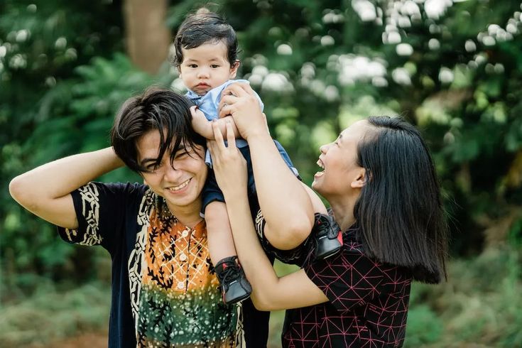 a woman holding a baby in her arms while standing next to two other women and smiling at the camera