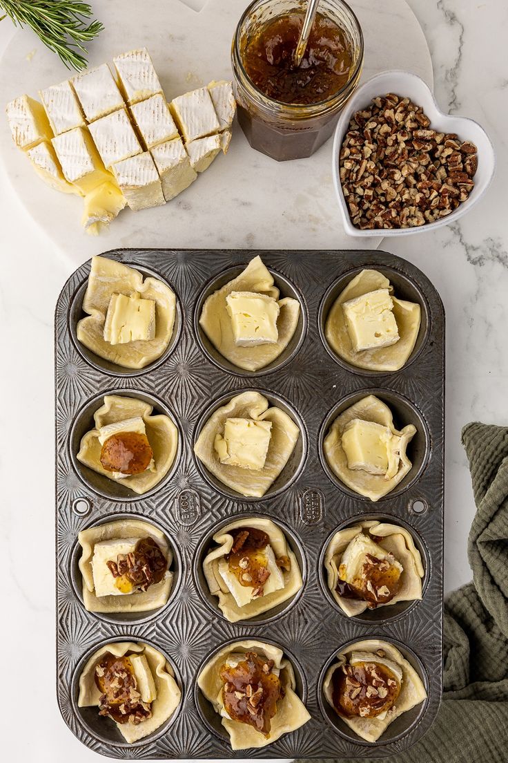 cupcake tins filled with pastries and toppings on a marble counter top