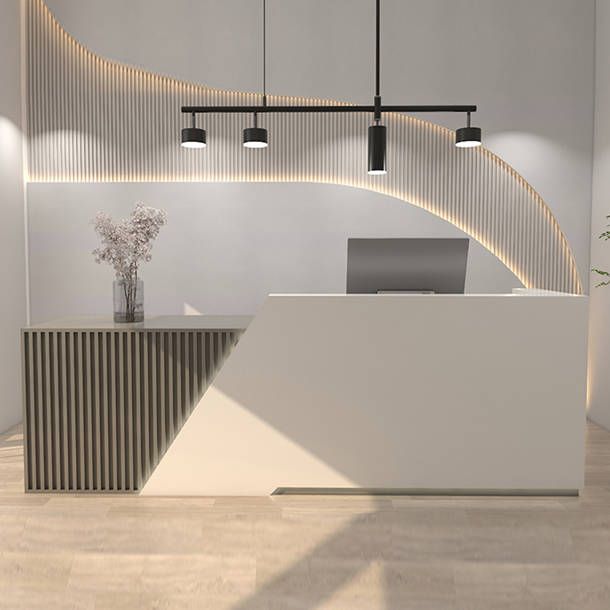 a white reception desk sitting in front of a plant on top of a hard wood floor