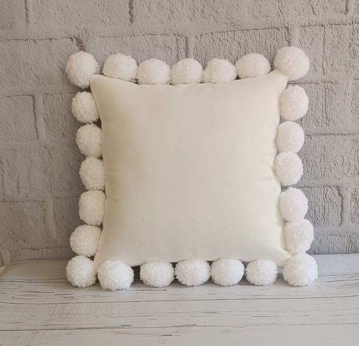 a white pillow with pom - poms on it