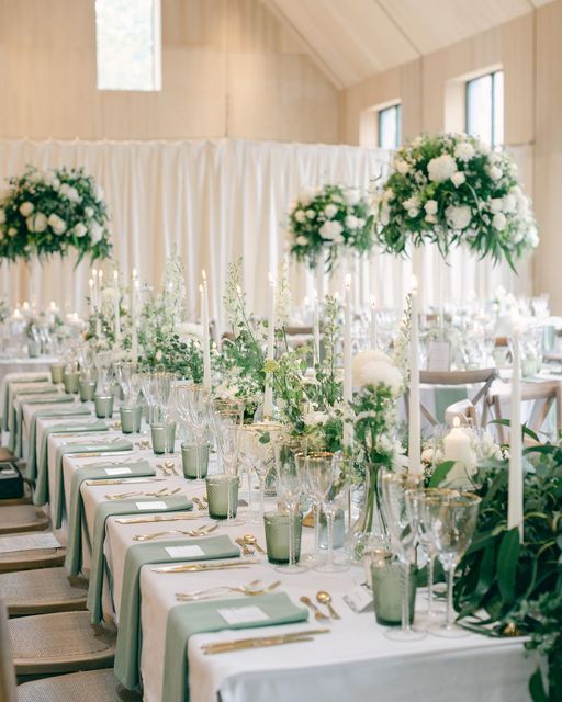 a long table is set with white flowers and greenery for an elegant wedding reception