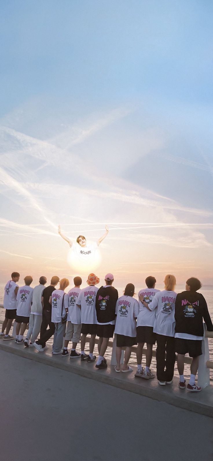 a group of people standing next to each other in front of the ocean at sunset