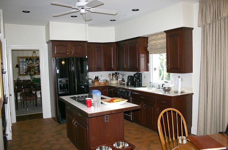 a kitchen with brown cabinets and white counter tops, along with a dining room table