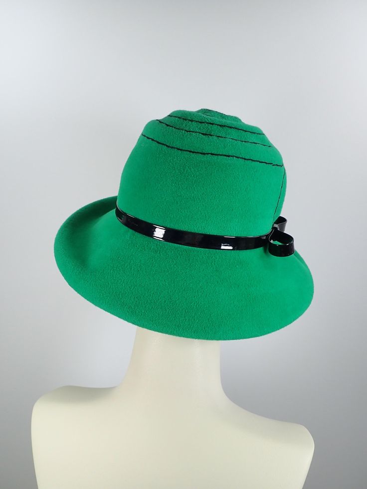 This pretty Kelly green medium brim hat is hand blocked over a vintage hat block and hand sewn. The asymmetrical brim rolls upward in the front and on the left side. Millinery wire is sewed inside of the brim edge to help the hat keep it's shape. The band is a gorgeous vintage patent leather with a matching bow. The top of the hat is hand embroidered in a swirl pattern in black cotton floss. An inner grosgrain headband helps avoid damage from makeup. Gorgeous in every way!+++++++++++++++++++++++ Green Hat Bands For Kentucky Derby, Adjustable Green Fedora Felt Hat, Green Fedora For Kentucky Derby, Fitted Green Fedora For Kentucky Derby, Adjustable Wide Brim Green Felt Hat, Green Fedora With Curved Brim For Spring, Green Short Brim Fedora For Spring, Spring Fitted Green Fedora, Green Fedora Felt Hat For Spring