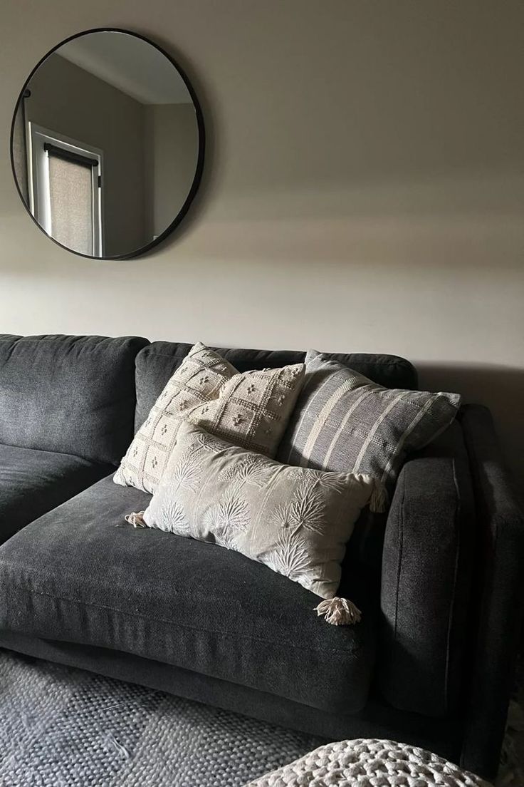 a living room with a couch, mirror and rug