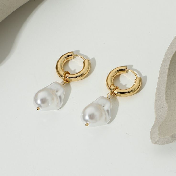 Indulge in the timeless elegance of Pearl Huggie Earrings, exquisitely crafted in 18k gold plating. These snug-fitting earrings blend the lustrous beauty of pearls with a contemporary huggie design. Elegant Huggie Clip-on Earrings, Elegant Gold Huggie Earrings With Pearl Charm, Elegant Gold Pearl Huggie Earrings, Classic 14k Gold Filled Earrings With Pearl Charm, Gold Pearl Huggie Earrings, Classic 14k Gold Filled Pearl Earrings, Classic 14k Gold-filled Pearl Earrings, Gold Huggie Pearl Earrings, Elegant Dangle Huggie Earrings In 14k Gold Filled