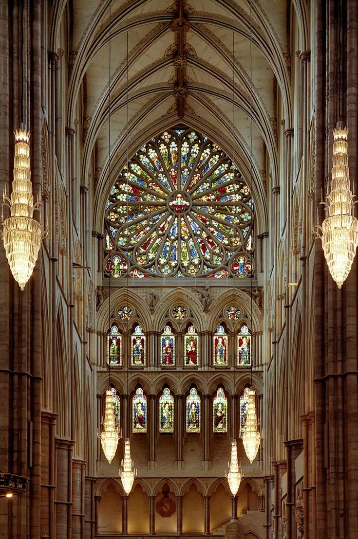 the inside of a cathedral with chandeliers and stained glass windows