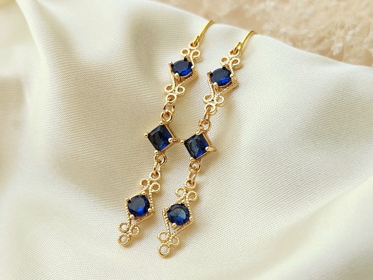 These elegant blue and gold earrings, are perfect for your special occasion! They feature sapphire blue zircon gemstones, in a high quality, 18k gold plated setting.  Product details: * 18k gold plated ear wires; Lead and nickle free * Zircon gemstones * 18k gold plated setting * Handmade, with lots of love and care! - Length:    2 inches - Width:     .25 inches ❤ You can click here to see more unique jewelry from Flutterbird: https://www.etsy.com/shop/FlutterbirdCo My goal is to provide every c Elegant Earrings Gold, Blue And Gold Earrings, Sapphire Blue Earrings, Dangle Earrings Wedding, Pretty Accessories, Gold Dangle Earrings, Earrings Elegant, Long Dangle Earrings, Earrings Wedding