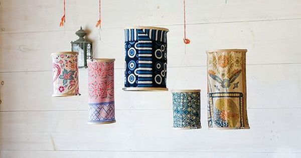 a dining room table with colorful chairs and vases hanging from the ceiling