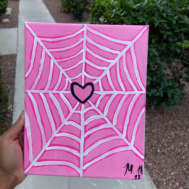 a hand holding up a pink paper with a black heart in the center on it