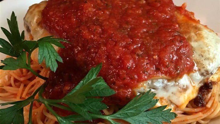 a plate of spaghetti with sauce and parmesan cheese on top, garnished with green leaves