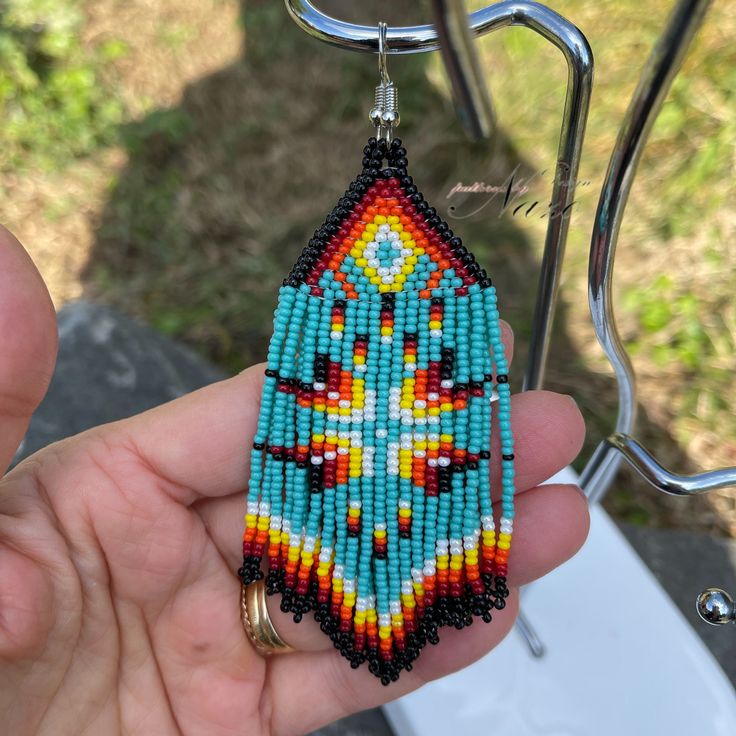 a person holding up a beaded pendant in their hand